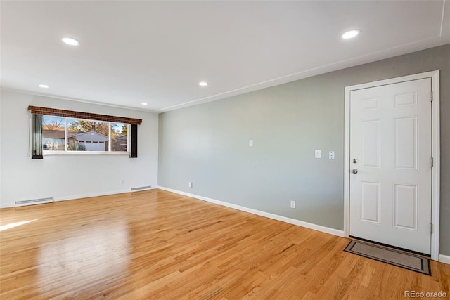 unfurnished room with baseboard heating, light wood-type flooring, and recessed lighting