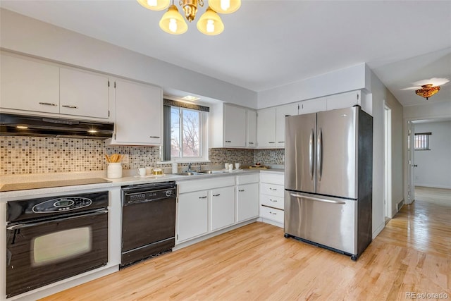 kitchen with white cabinets, under cabinet range hood, light countertops, black appliances, and backsplash