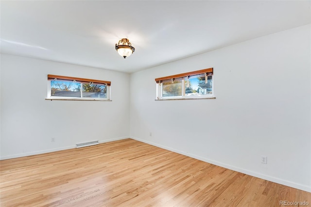 unfurnished room featuring plenty of natural light, visible vents, light wood-style flooring, and baseboards