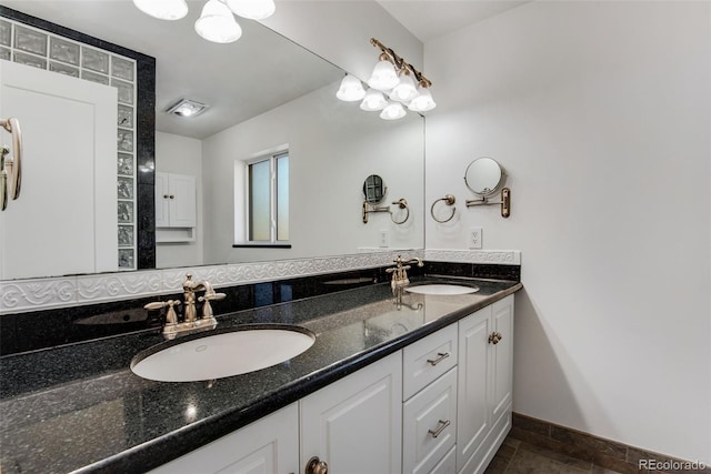 full bathroom with double vanity, baseboards, and a sink