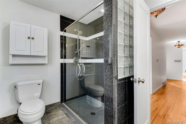 bathroom featuring toilet, a shower stall, and baseboards