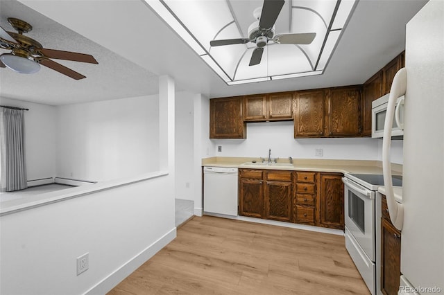 kitchen with white appliances, ceiling fan, light countertops, a sink, and light wood finished floors