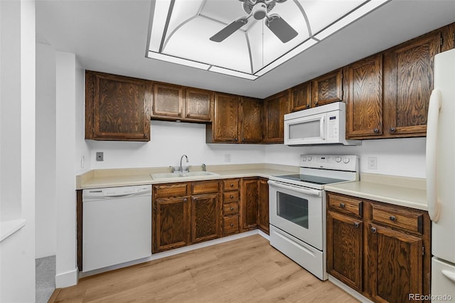 kitchen featuring a ceiling fan, white appliances, light wood-type flooring, light countertops, and a sink