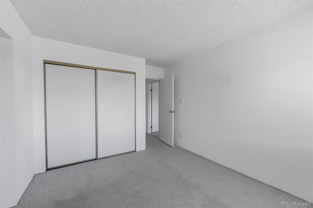 unfurnished bedroom featuring carpet floors, a textured ceiling, and a closet