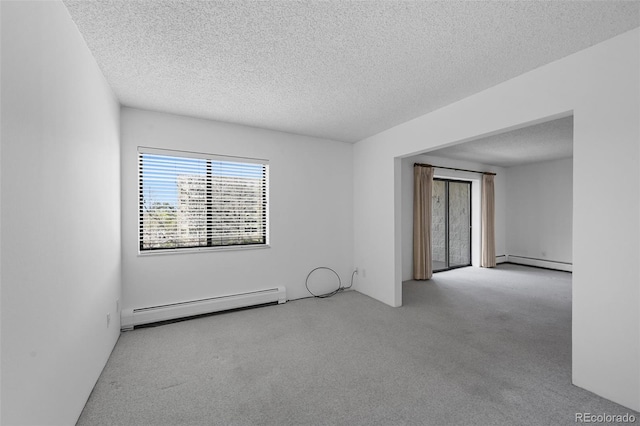 unfurnished room featuring a textured ceiling, baseboard heating, and carpet