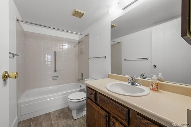 full bath with visible vents, wood finished floors, shower / washtub combination, vanity, and toilet
