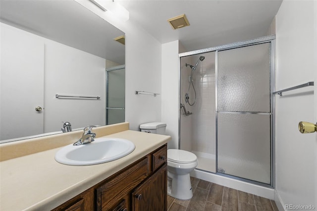 full bathroom featuring vanity, toilet, wood finished floors, and a stall shower