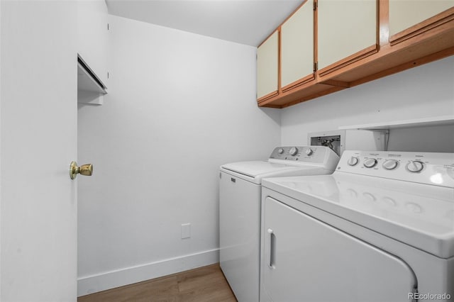 washroom featuring baseboards, light wood-type flooring, cabinet space, and washing machine and clothes dryer