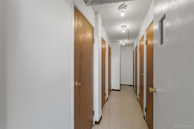 hall featuring a textured ceiling and baseboards
