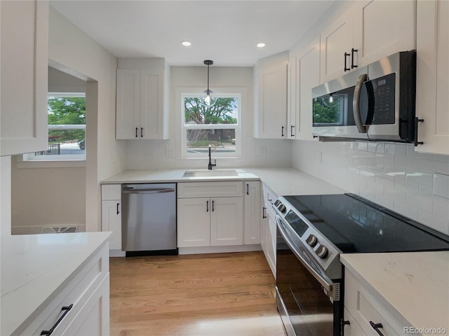 kitchen with white cabinetry, pendant lighting, and stainless steel appliances