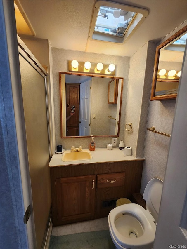 bathroom with vanity, toilet, tile patterned flooring, and a shower with door