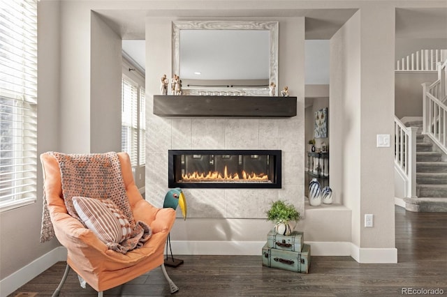 living area with a tiled fireplace and dark hardwood / wood-style floors