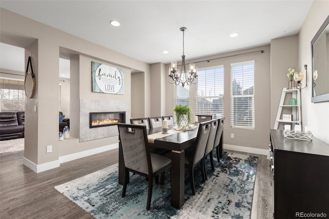 dining area featuring dark hardwood / wood-style flooring, a fireplace, a notable chandelier, and a wealth of natural light