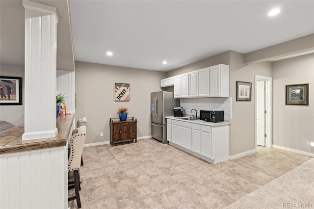 kitchen featuring white cabinets, sink, stainless steel fridge, and backsplash