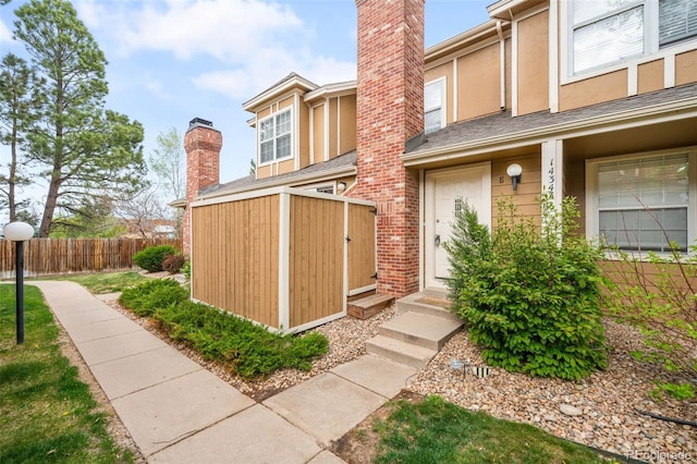 14343 E Dickinson Dr Unit E, Aurora, CO 80014 - doorway to property featuring fence, a chimney, and stucco siding