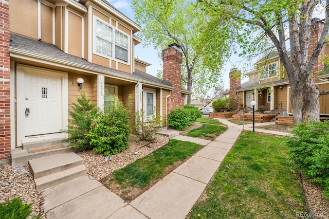 14343 E Dickinson Dr Unit E, Aurora, CO 80014 - view of front of home with a shingled roof, stucco siding, entry steps, and a front lawn