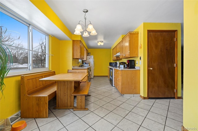 kitchen with white appliances, light tile patterned floors, an inviting chandelier, and decorative light fixtures