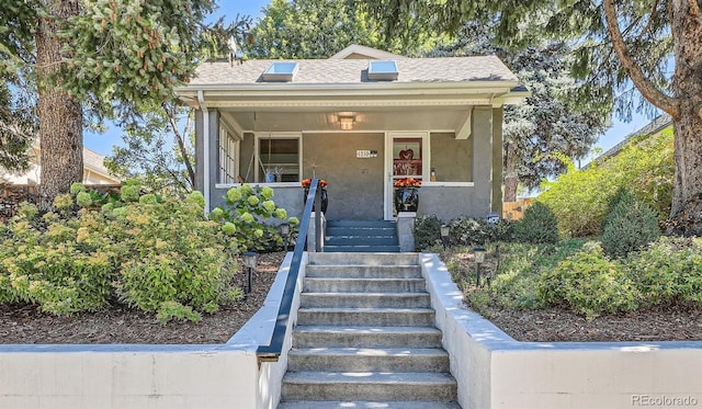 view of front of house with a shingled roof, stairs, and stucco siding