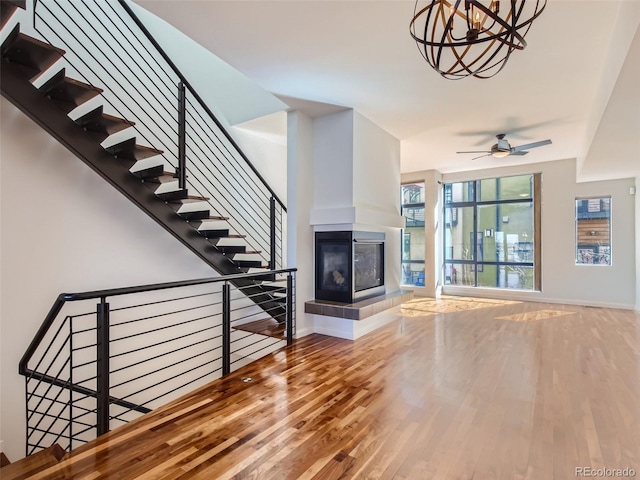 unfurnished living room with ceiling fan, a multi sided fireplace, and hardwood / wood-style floors