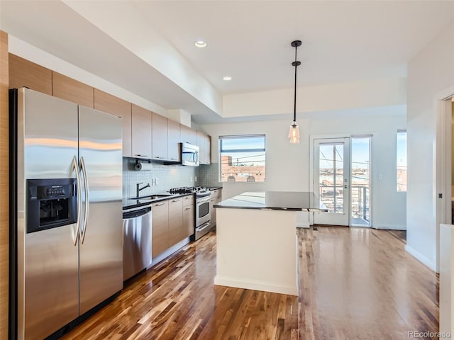 kitchen with dark hardwood / wood-style floors, decorative backsplash, sink, hanging light fixtures, and appliances with stainless steel finishes