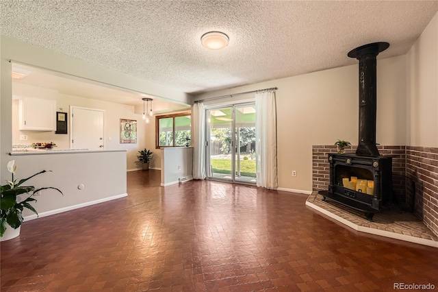 10247 W Arkansas Ave, Lakewood, CO 80232 - unfurnished living room with a wood stove, a textured ceiling, and baseboards