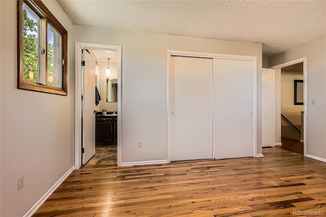 10247 W Arkansas Ave, Lakewood, CO 80232 - unfurnished bedroom with wood finished floors, a closet, a textured ceiling, connected bathroom, and baseboards