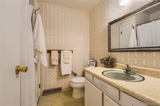 10247 W Arkansas Ave, Lakewood, CO 80232 - full bathroom with vanity, toilet, wallpapered walls, and baseboards