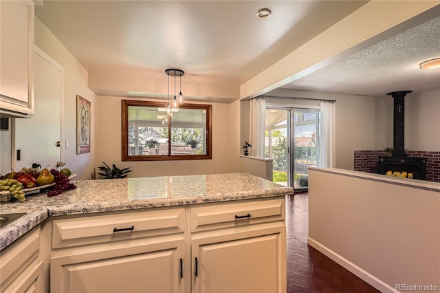 10247 W Arkansas Ave, Lakewood, CO 80232 - kitchen with a wood stove, light stone countertops, white cabinets, brick patterned flooring, and decorative light fixtures