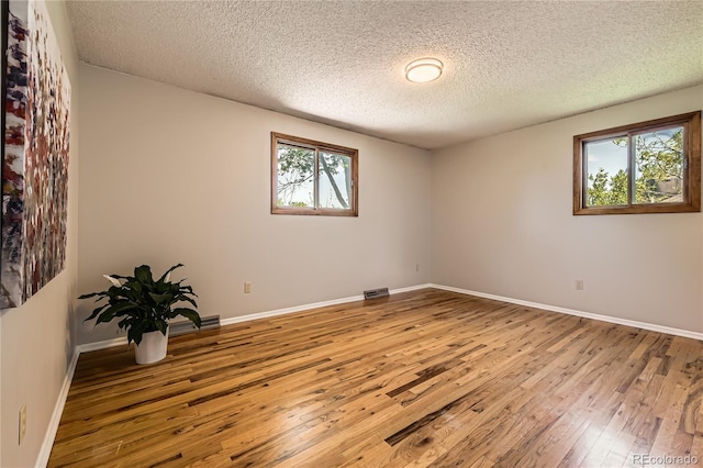 10247 W Arkansas Ave, Lakewood, CO 80232 - unfurnished room with wood-type flooring, plenty of natural light, a textured ceiling, and baseboards