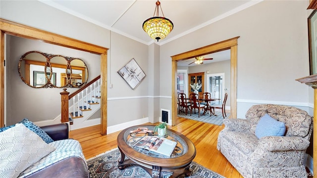 living room with stairs, baseboards, wood finished floors, and crown molding