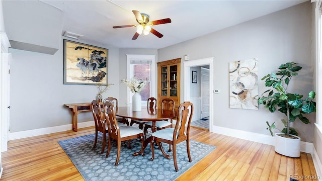 dining space featuring light wood-style flooring, baseboards, and a ceiling fan