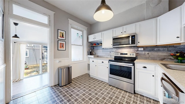 kitchen with stainless steel appliances, light countertops, white cabinets, and decorative backsplash