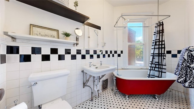 bathroom featuring a freestanding tub, toilet, tile walls, a shower, and tile patterned floors