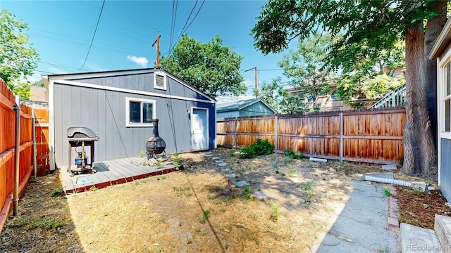 view of yard featuring an outdoor structure, a fenced backyard, and a wooden deck