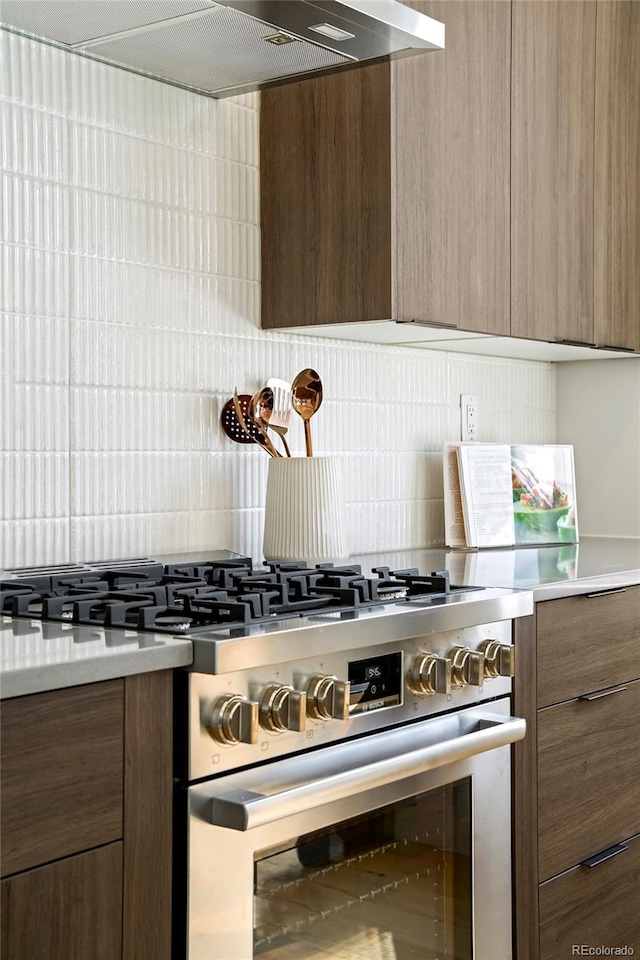 kitchen with ventilation hood, tasteful backsplash, and high end range