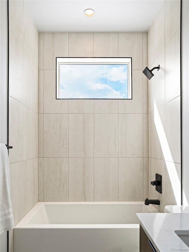 bathroom featuring tiled shower / bath, vanity, and a healthy amount of sunlight