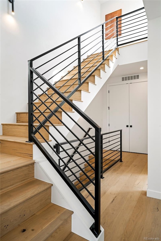 stairs featuring a towering ceiling and hardwood / wood-style floors