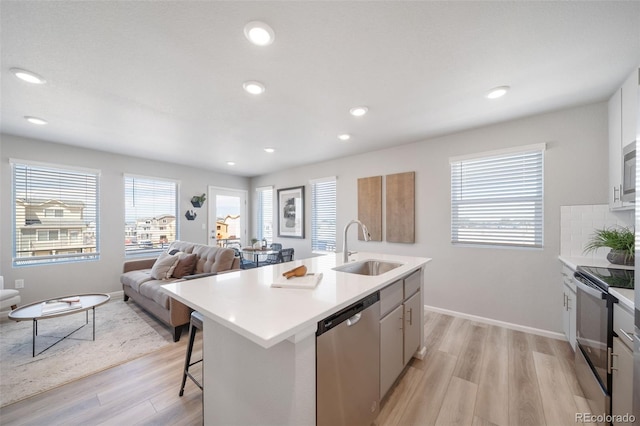 13616 E 103rd Pl, Commerce City, CO 80022 - kitchen featuring stainless steel appliances, light wood-style flooring, a center island with sink, light countertops, and a breakfast bar area