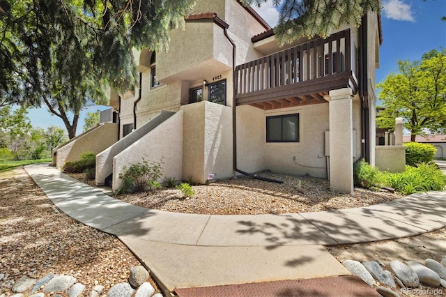 view of side of property with stucco siding and a balcony