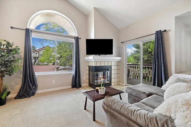 carpeted living room with a tiled fireplace, baseboards, and high vaulted ceiling