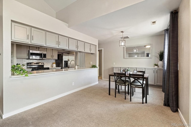 kitchen with appliances with stainless steel finishes, light colored carpet, backsplash, baseboards, and light countertops