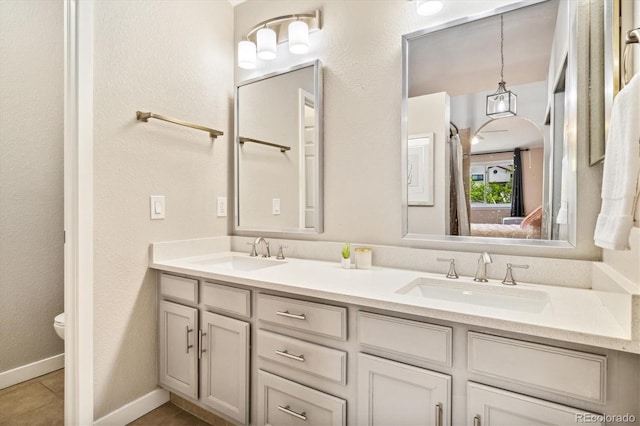 bathroom with double vanity, toilet, tile patterned flooring, and baseboards