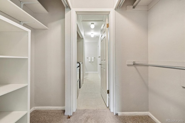 spacious closet featuring light colored carpet, light tile patterned flooring, and attic access