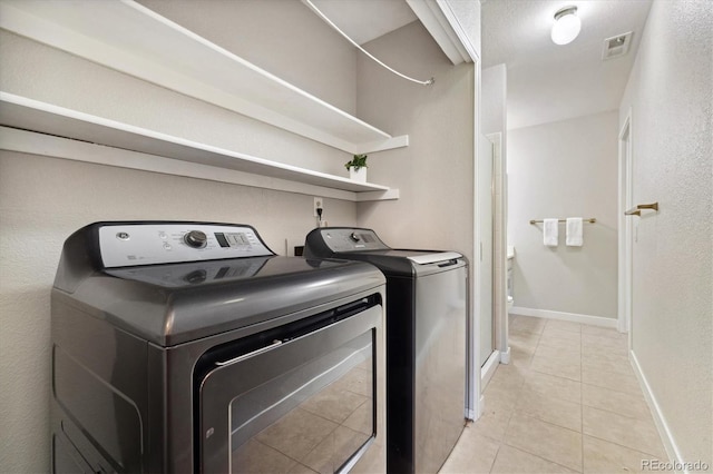 laundry area featuring washer and dryer, light tile patterned floors, and baseboards