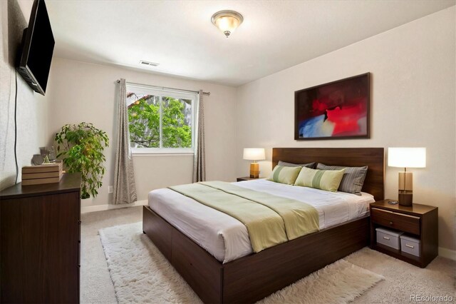bedroom with light colored carpet and baseboards