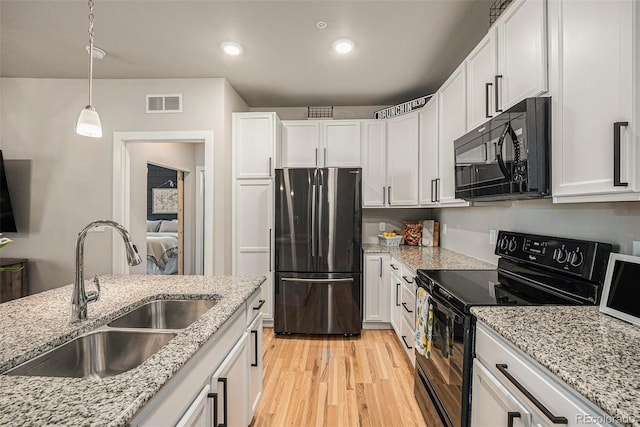 15274 W 64th Ln Unit 206, Arvada, CO 80007 - kitchen featuring visible vents, light wood-style flooring, a sink, black appliances, and white cabinetry