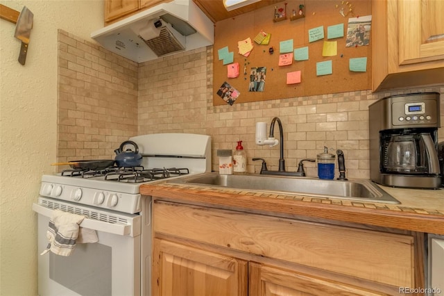 kitchen featuring gas range gas stove, sink, light brown cabinets, tasteful backsplash, and range hood