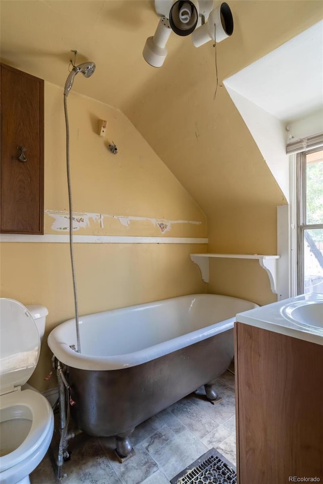 bathroom with vanity, vaulted ceiling, toilet, and a bathtub