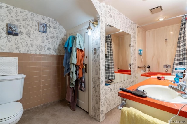 bathroom featuring vanity, toilet, and tile walls