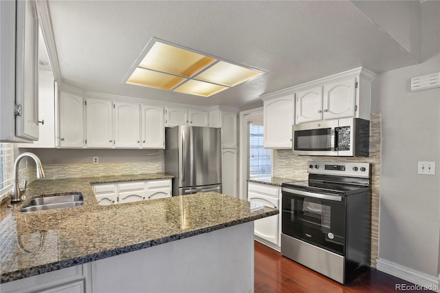 kitchen with stainless steel appliances, white cabinetry, sink, and kitchen peninsula